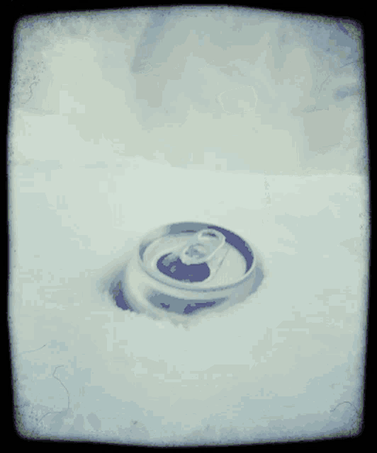a can of soda is sitting in the snow with its lid open