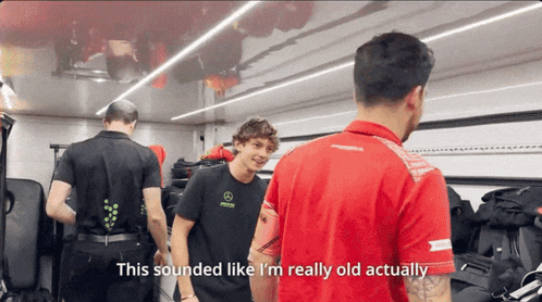 a man in a mercedes shirt talks to another man in a red shirt