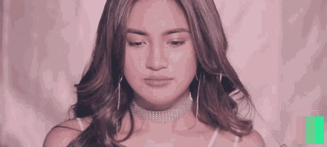 a woman wearing a choker and earrings looks at the camera .