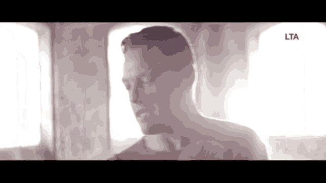 a man in a blue shirt is standing in front of a window in a room .