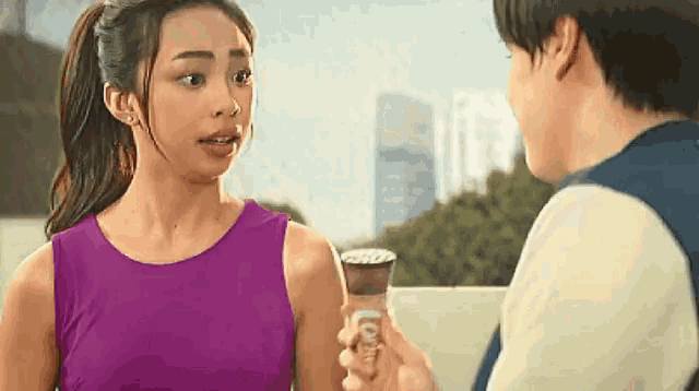a woman in a purple tank top is talking to a man in a white shirt .