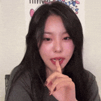 a woman with long hair is holding her finger to her mouth