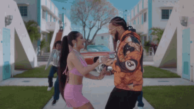 a man and a woman are dancing on a sidewalk in front of a building