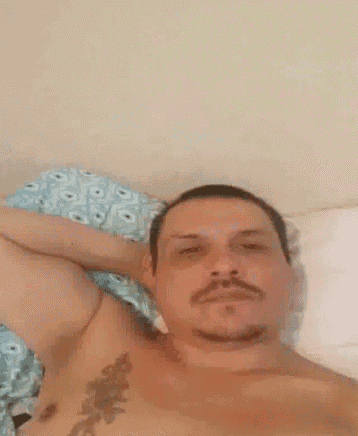 a shirtless man with a tattoo on his chest is laying in bed .