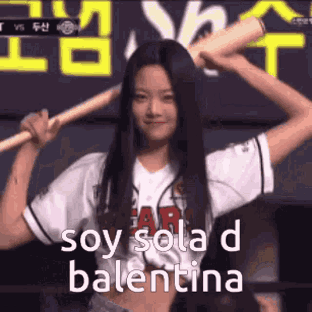 a woman in a baseball uniform is holding a bat over her head and says soy sola d balentina .