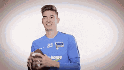 a young man wearing a blue jersey with the number 33 on it is holding a football