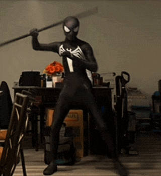 a man in a spiderman costume is holding a stick in his hand