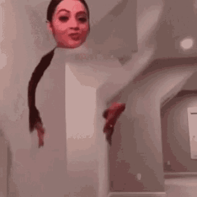 a woman is standing in a room with her head sticking out of the wall .