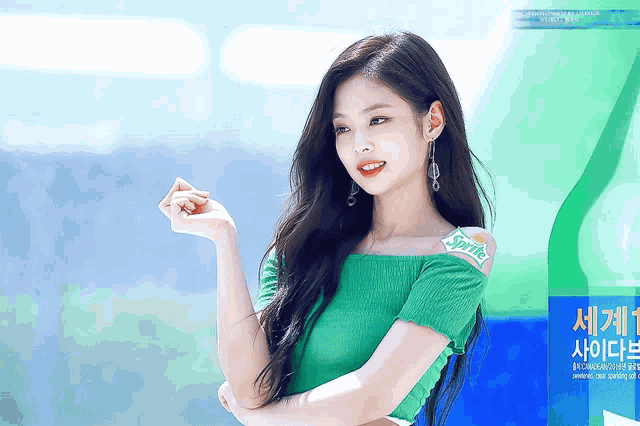a woman in a green off the shoulder top stands in front of a bottle of sprite