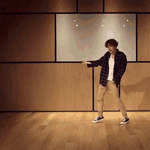 a man in a plaid shirt is dancing in a room