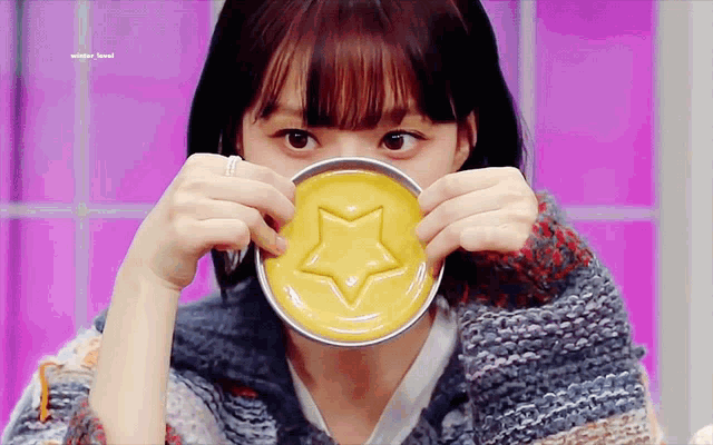 a woman is holding a yellow candy with a star on it in front of her face