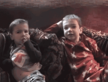 two young boys are sitting on a couch and one of them has a shirt that says nike