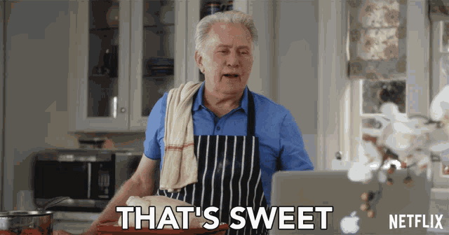 an older man in an apron says that 's sweet in front of an apple laptop
