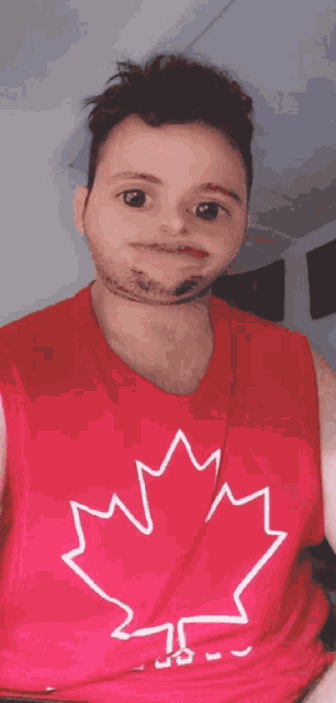 a man wearing a red tank top with a white maple leaf on it