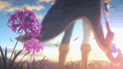 a person standing next to purple flowers in the grass