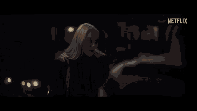 a woman in a dark room with a netflix logo on the bottom