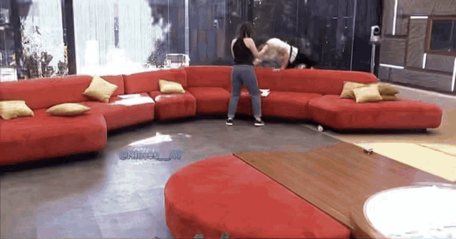 a woman is standing next to a large red couch in a living room