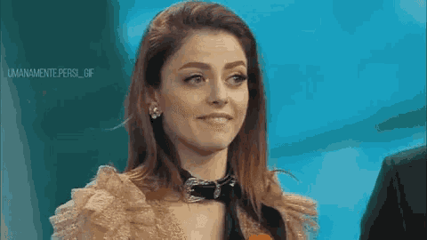 a woman wearing a choker is smiling and looking at the camera .