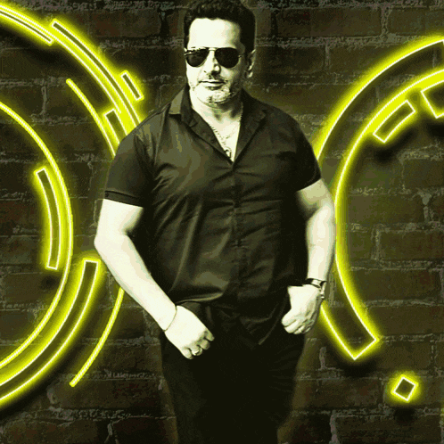 a man wearing sunglasses and a black shirt is standing in front of a neon sign