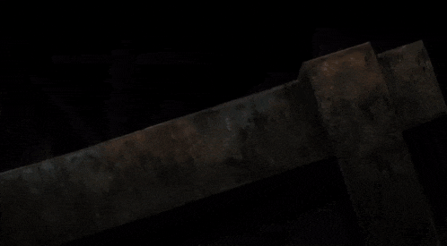 a man in a black suit is kneeling on a wooden table in the dark