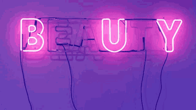 the word beauty is written in neon lights on a purple background .