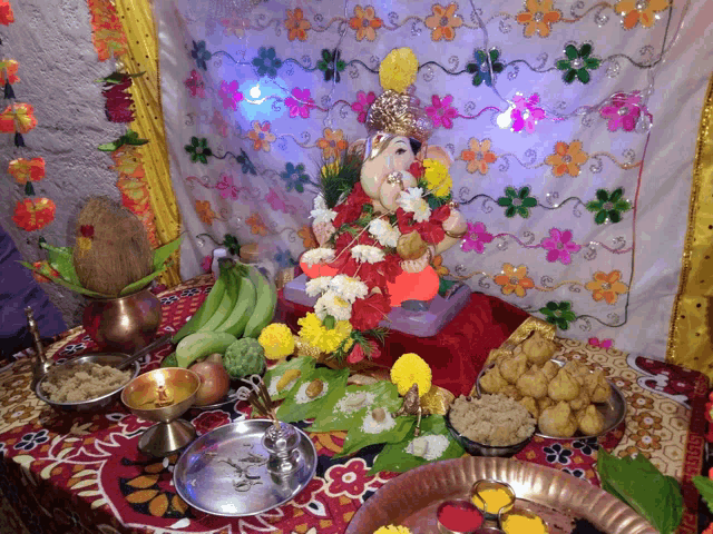 a statue of ganesha sits on a table surrounded by plates of food