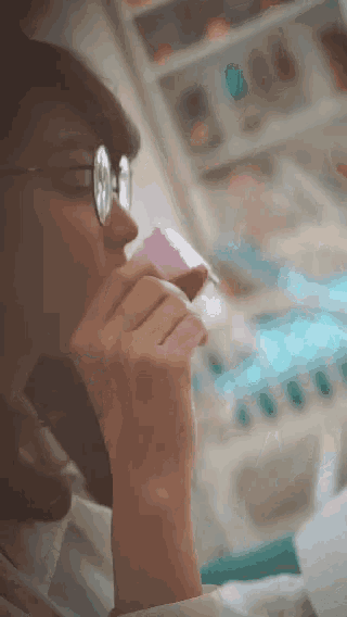 a woman wearing glasses is drinking from a purple container