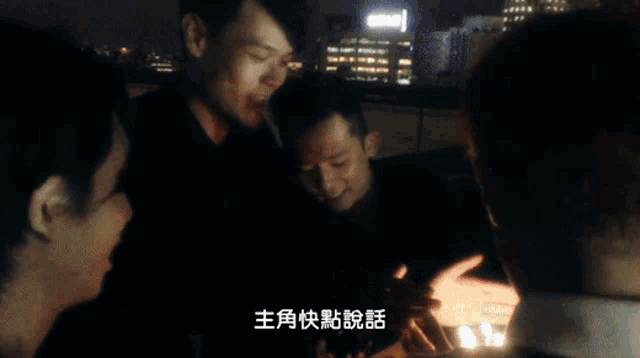 a group of people gathered in a dark room with chinese writing on the bottom right