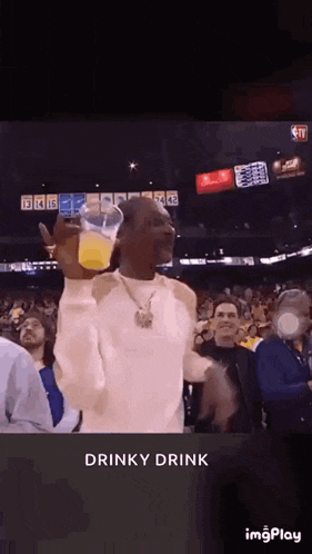 snoop dogg is holding a cup of orange juice in front of a crowd of people .