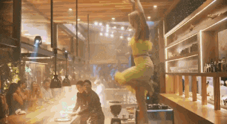 a woman in a yellow dress is jumping in the air in a restaurant