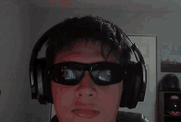 a man wearing sunglasses and headphones looks at the camera