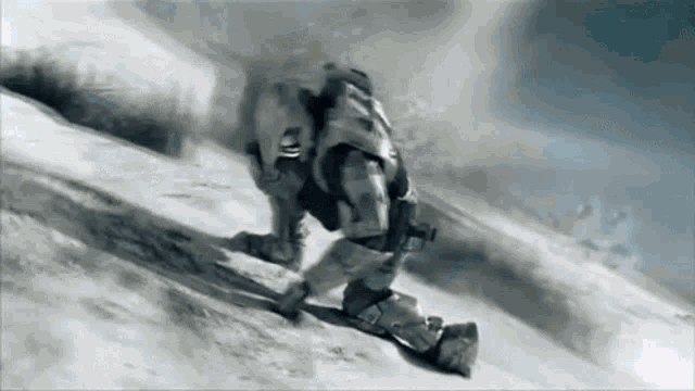 a man in a military uniform is crawling down a snowy hill .