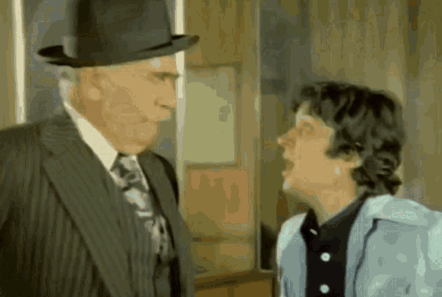 a man in a suit and top hat is talking to another man