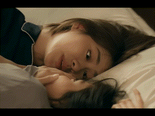 a woman is laying on a bed with her head on another person 's lap .
