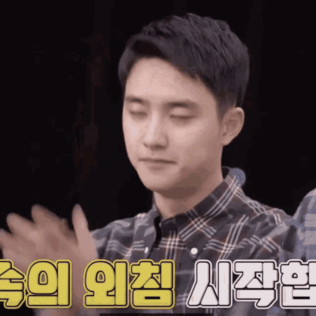 a young man in a plaid shirt is clapping his hands in korean .