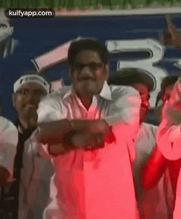 a group of men are standing next to each other and dancing in front of a crowd .