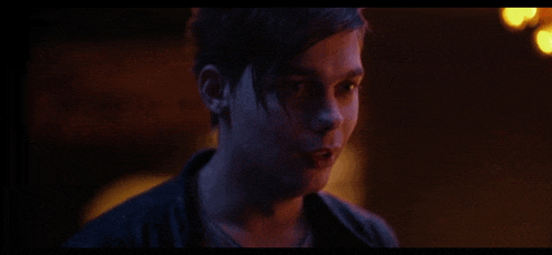 a close up of a young man 's face in a dark room looking at the camera .