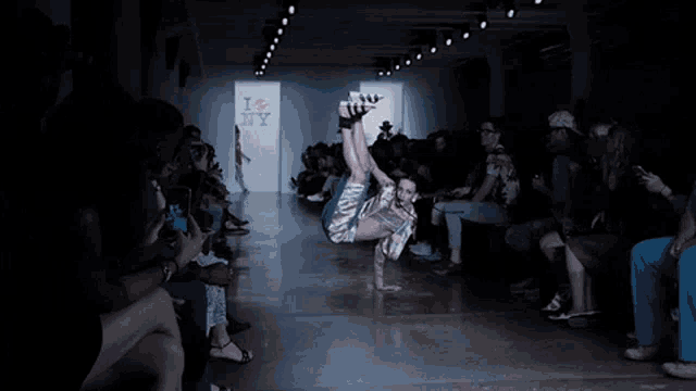 a person doing a handstand on a runway with a sign that says i & ny