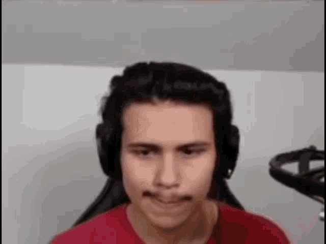 a man wearing headphones and a red shirt is sitting in a chair .