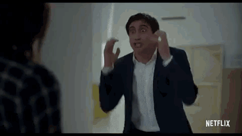 a man in a suit and white shirt is making a funny face while talking to a woman .