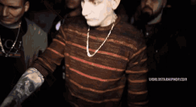 a man in a striped sweater is dancing in a dark room with the words worldstarhiphop.com visible in the corner
