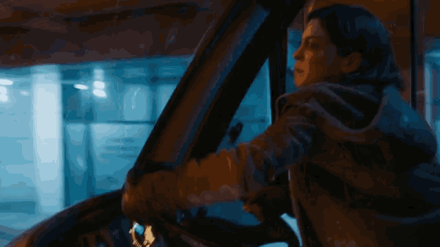 a woman is driving a car at night and holding the steering wheel