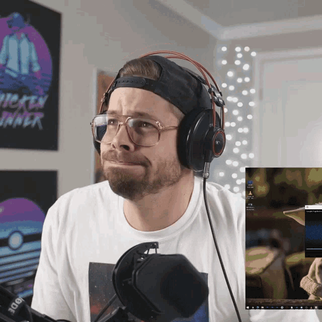 a man wearing headphones looks at a screen with a chicken dinner poster behind him