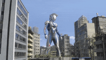 a statue of a man in a silver and blue suit stands in a city