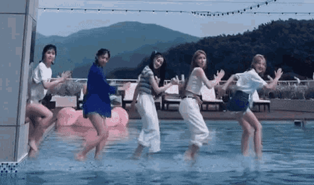 a group of women are dancing in a pool .