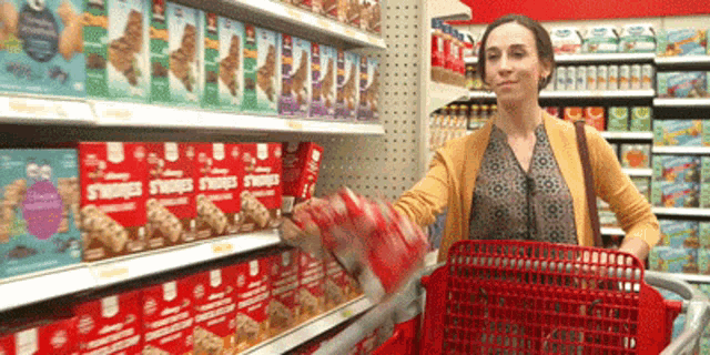 a woman pushing a shopping cart in a grocery store with boxes of s'mores on the shelves behind her
