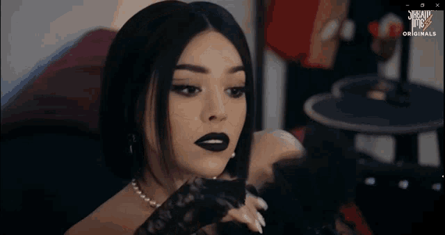 a woman wearing black gloves and a necklace is on a screen that says scream at me