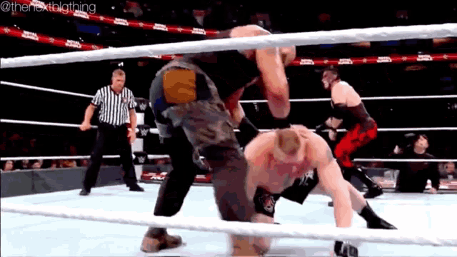 two men are wrestling in a wrestling ring while a referee watches .