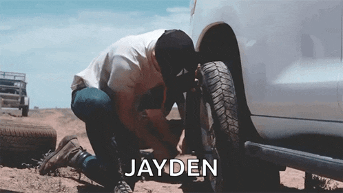 a man is working on a tire with the name jayden written above him