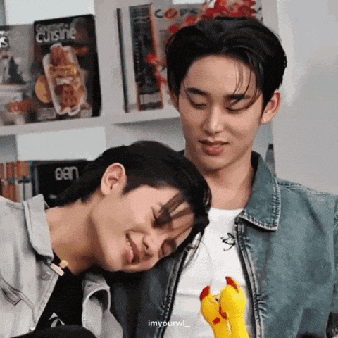 two young men are sitting next to each other with one holding a stuffed chicken